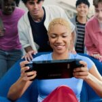 A gamer playing the Lenovo Legion Go gaming handheld PC with other people looking on.