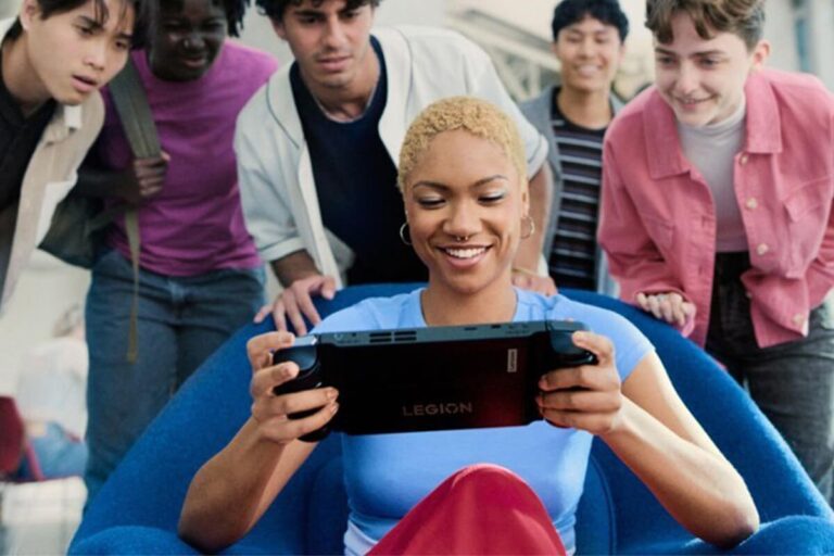 A gamer playing the Lenovo Legion Go gaming handheld PC with other people looking on.
